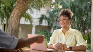 woman smiling at table outside with laptop